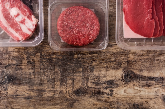 Foto diferentes tipos de carne embalados em plástico na mesa de madeira