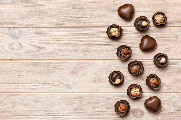 Diferentes tipos de chocolates na mesa colorida, vista superior e postura plana com espaço de cópia