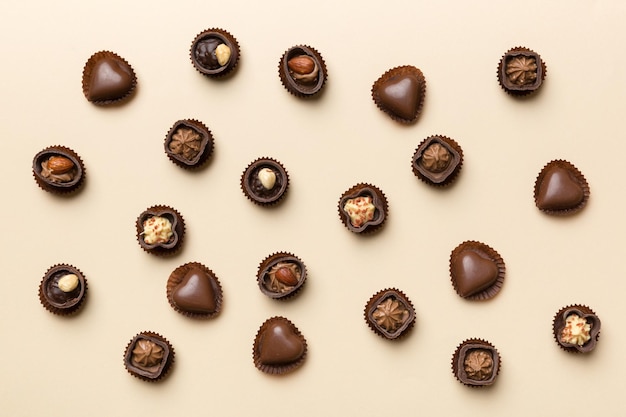 Diferentes tipos de chocolates na mesa colorida, vista superior e postura plana