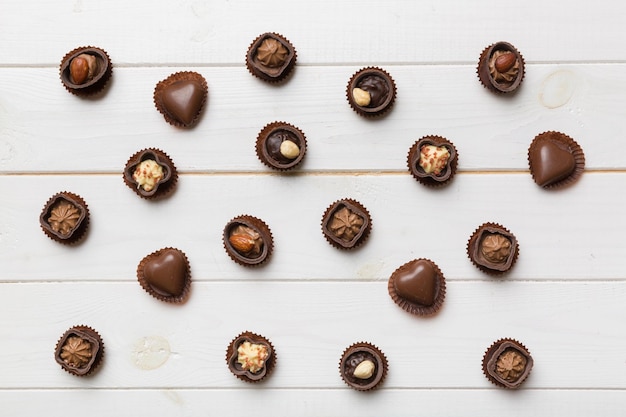 Diferentes tipos de chocolates na mesa colorida, vista superior e postura plana