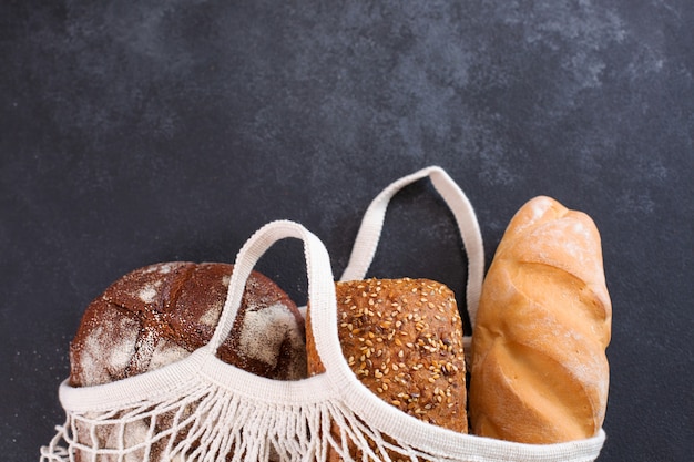 Diferentes tipos de pão fresco em sacola de malha branca