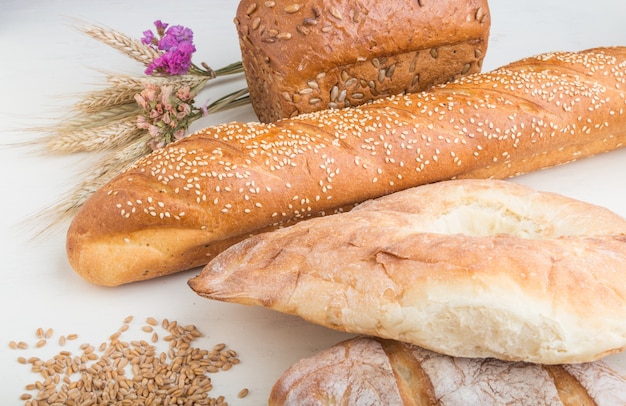 Diferentes tipos de pão fresco em uma superfície de madeira branca. vista lateral.