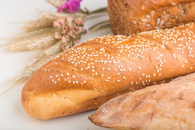 Diferentes tipos de pão fresco em uma superfície de madeira branca. vista lateral.