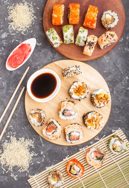 Diferentes tipos de rolos de sushi maki com salmão, gergelim, queijo, ovas e pauzinhos, molho de soja