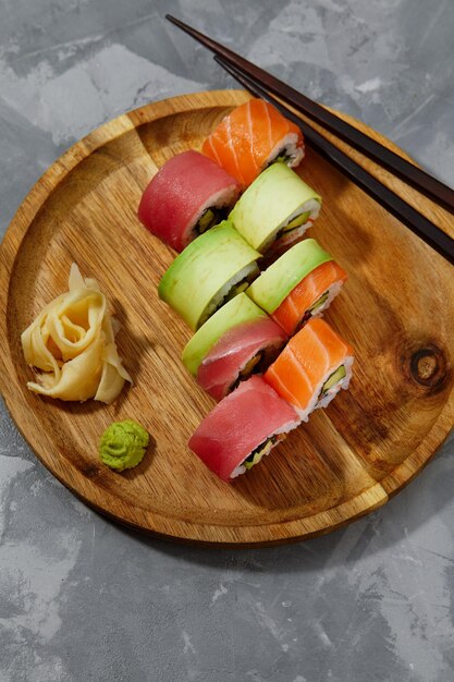 Diferentes tipos de sushi e rolos deliciosos e suculentos em uma tábua de madeira