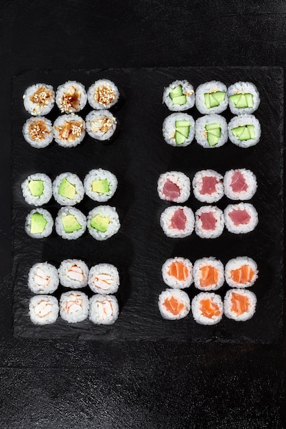 Diferentes tipos de sushi e rolos deliciosos e suculentos em uma tábua de madeira