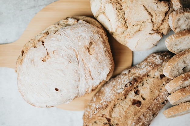 Diferentes tipos de pan artesanal y orgánico recién horneado sobre una mesa rústica Cocina casera Pan de masa fermentada con corteza crujiente en un estante de madera Concepto de productos de panadería Restaurante y productos