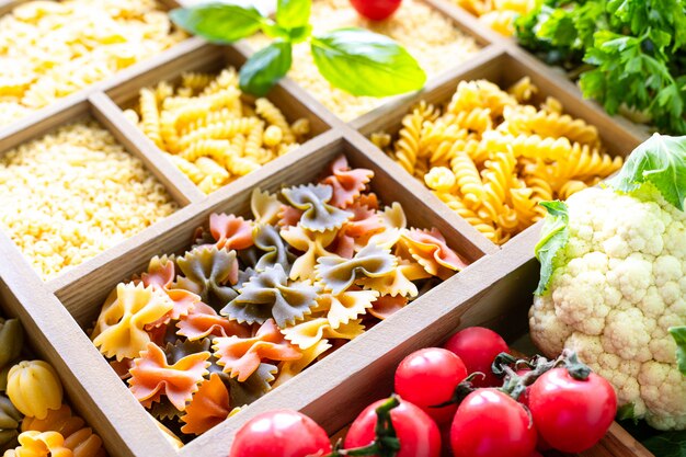 Diferentes tipos de pasta sin cocer en caja de madera, pasta integral, pasta, espagueti, fideos, tallarines. Copia espacio