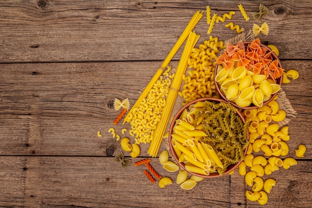 Diferentes tipos de pasta en cuencos de cerámica. Comida tradicional italiana, concepto de alimentación saludable. Mesa rústica de madera