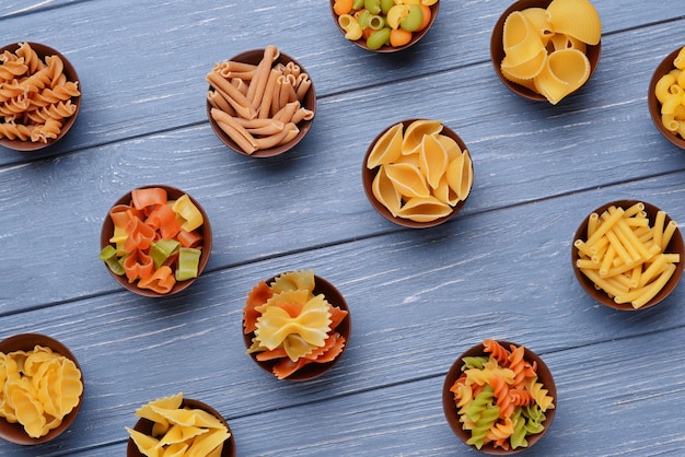 Diferentes tipos de pasta en tazones sobre fondo de madera