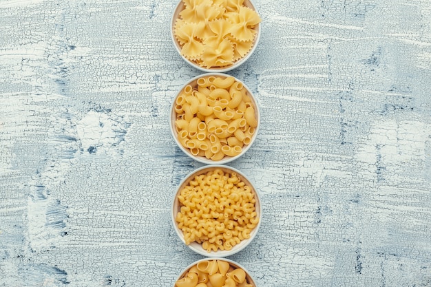 Foto diferentes tipos de pasta en tazones sobre la mesa.