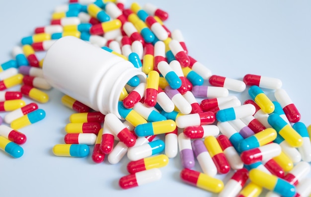 Diferentes tipos de pastillas, medicamentos en diferentes colores sobre fondo azul, vista superior plana