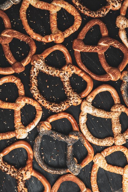 Diferentes tipos de pretzels horneados con semillas sobre un fondo negro