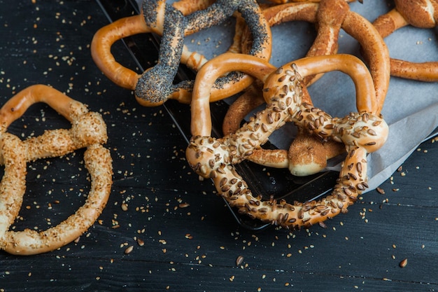 Diferentes tipos de pretzels o bagels horneados con semillas sobre un fondo negro