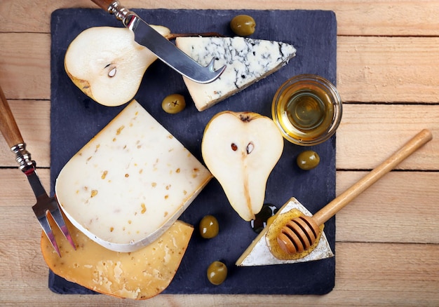 Diferentes tipos de queso con miel sobre mesa de madera