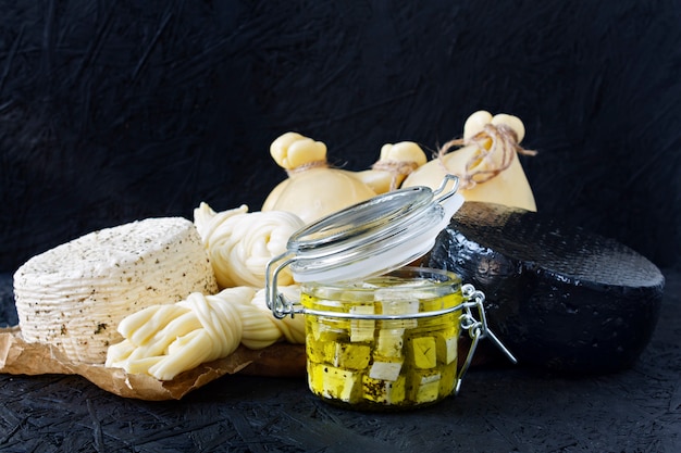 Foto diferentes tipos de queso sobre un fondo negro. tabla de quesos