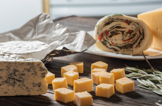 Diferentes tipos de quesos, uvas rojas, aperitivos en mesa de madera, rústica. Bodegón queso