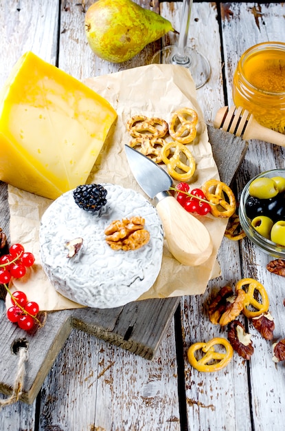 Diferentes tipos de quesos en una vieja mesa de madera blanca.