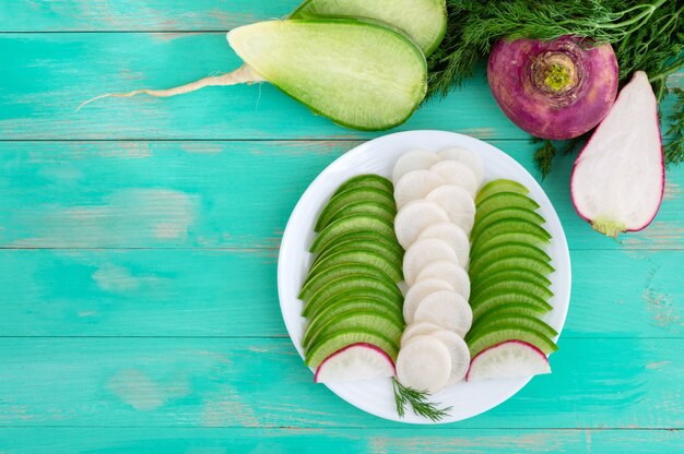 Diferentes tipos de rábano, cortado en rodajas en un plato blanco. Un vegetal de raíz de vitamina útil, un ingrediente para ensaladas. La vista superior. Endecha plana