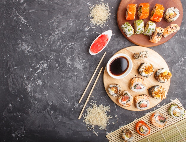 Diferentes tipos de rollos de sushi maki con salmón sobre un fondo de hormigón negro