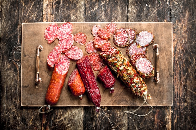 Diferentes tipos de salami en las tablas. Sobre un fondo de madera.