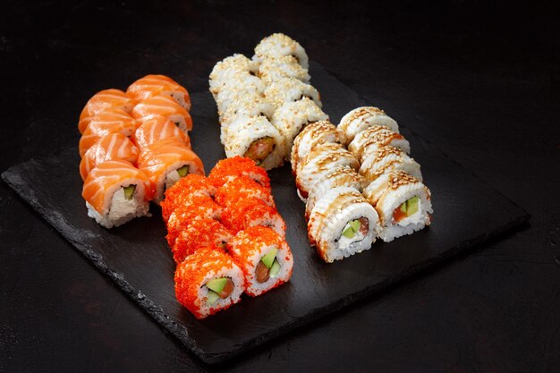 Diferentes tipos de sushi y rollos deliciosos y jugosos en una tabla de madera