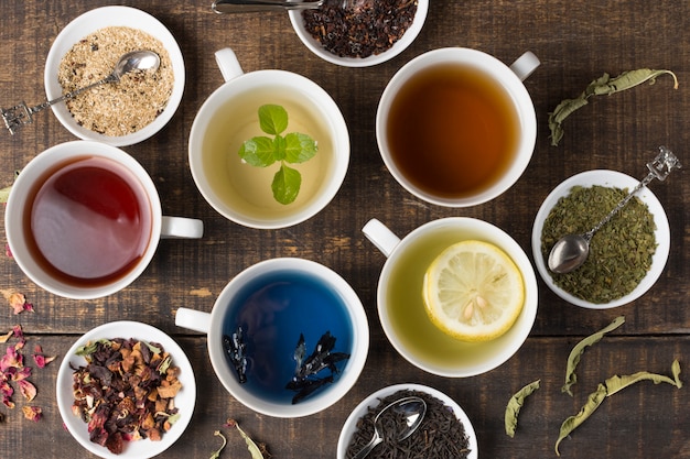 Diferentes tipos de tazas de té de aroma blanco con hierbas en mesa de madera