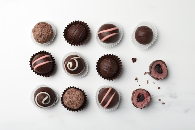 Diferentes trufas de chocolate deliciosas sobre una mesa de mármol blanco plana