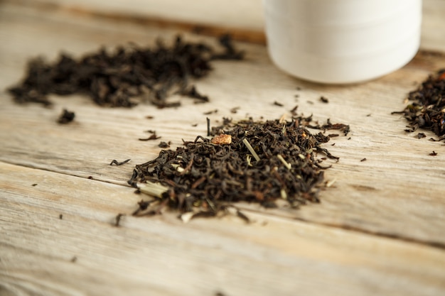 Diferentes variedades de té natural en una cuchara y preparado en un vaso sobre un fondo de madera.