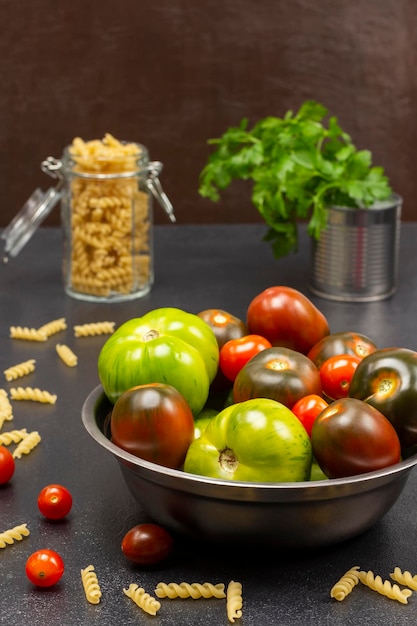 Diferentes variedades de tomates verdes y rojos en una lata de metal Pasta en un tarro de cristal