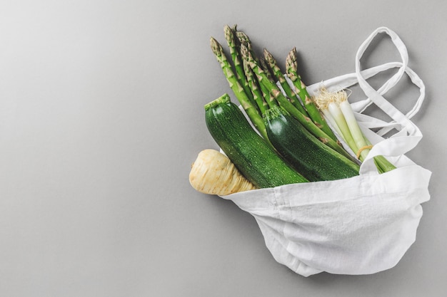 Foto diferentes vegetales en bolsa textil en copyspace gris