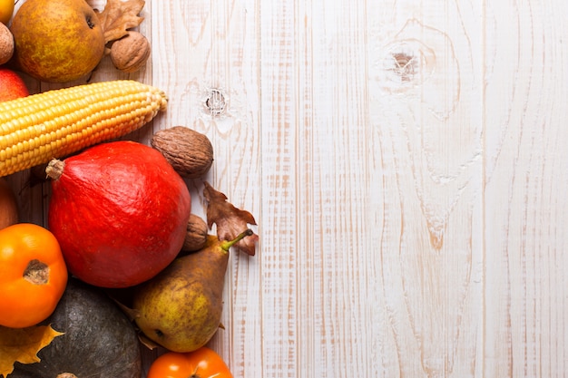 Diferentes verduras calabazas, manzanas, peras, nueces, maíz, tomates, hojas amarillas secas sobre fondo blanco de madera. Cosecha de otoño, copyspace.