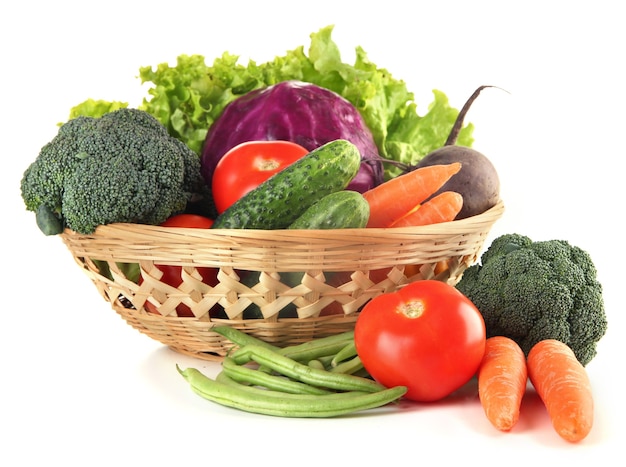 Diferentes verduras en canasta aislado en blanco