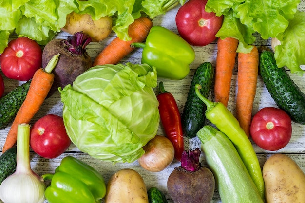 Diferentes verduras de colores por toda la mesa en fotograma completo. Alimentación saludable