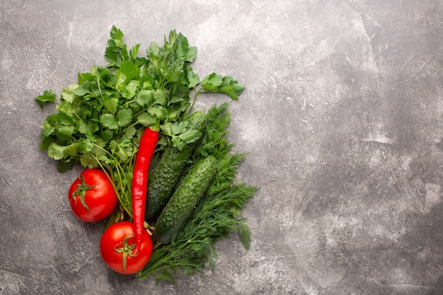 Diferentes verduras frescas, tomates, pepino y chile sobre hormigón gris. Vista superior.