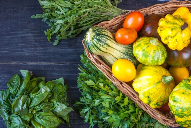 Diferentes verduras de otoño en una cesta en una mesa de madera