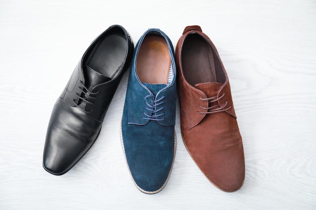Diferentes zapatos masculinos sobre suelo de madera.