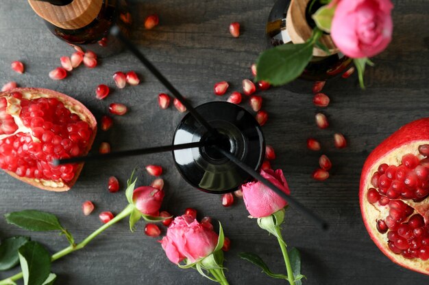 Diffusoren, Blumen und Granatapfel auf dunklem Holztisch