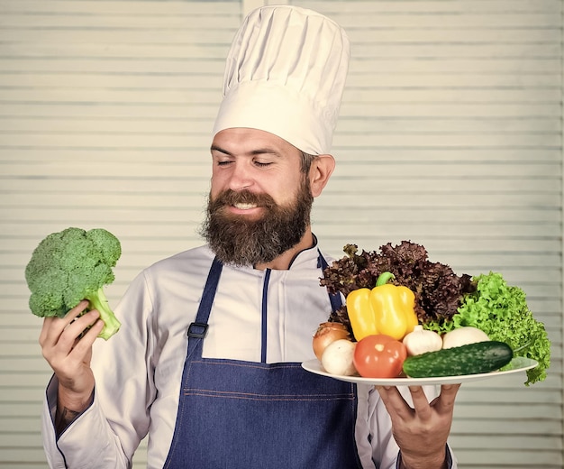 Difícil elección Ensalada vegetariana con verduras frescas Cocina de comida sana Hipster maduro con barba Cocina culinaria Vitamina Dieta comida orgánica Receta de chef de hombre barbudo feliz