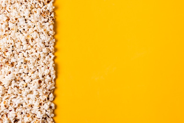 Difundir las palomitas de maíz sobre fondo amarillo