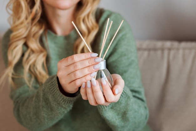 Difusor de aromas para el hogar en manos de mujer con manicura nude