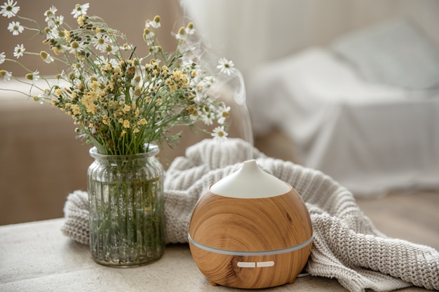 Difusor de aroma de óleo moderno na sala de estar em cima da mesa com elemento de malha e flores.