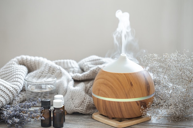 Difusor de óleo de aroma moderno em superfície de madeira com elemento de malha, água e óleos em potes.