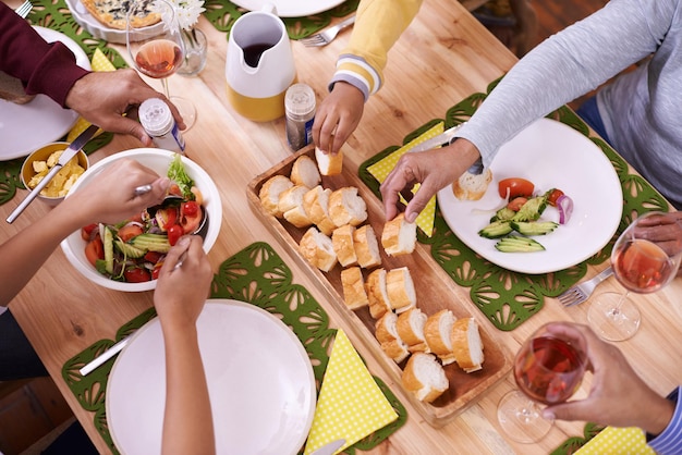 Dig in Eine ausgeschnittene, erhöhte Ansicht einer Gruppe von Menschen, die eine Mahlzeit an einem Tisch teilen