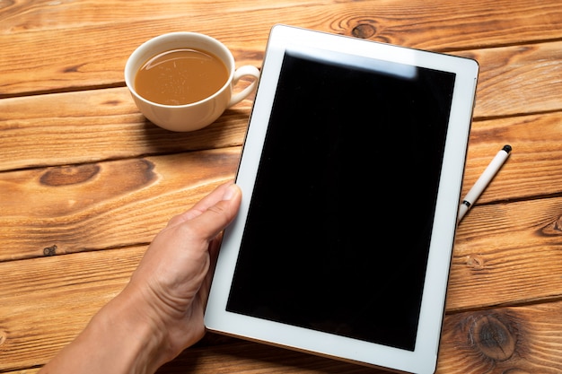 Digital tablet e xícara de café na mesa de madeira