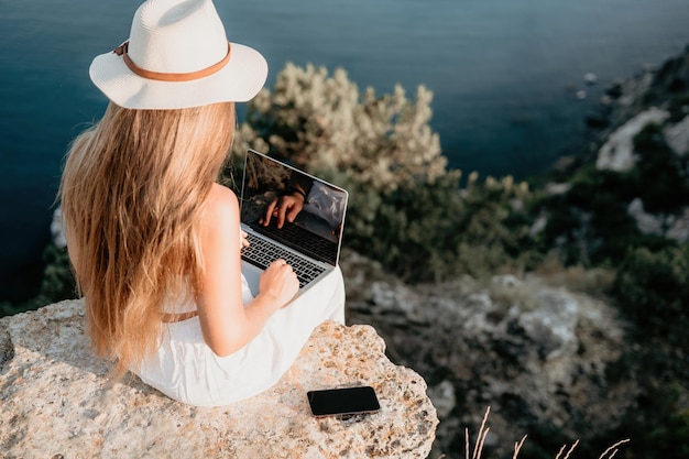 Digitale nomadische Geschäftsfrau, die am Meer am Laptop arbeitet hübsche Dame, die am Meer am Computer tippt