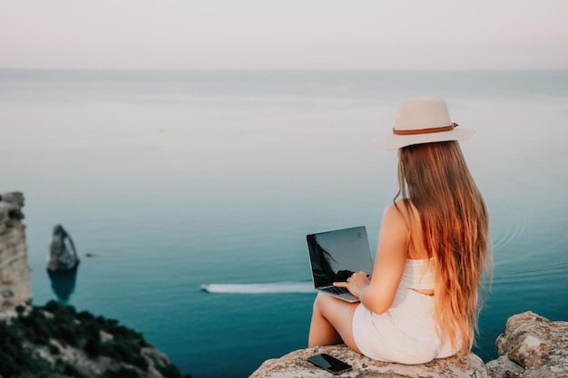 Digitale nomadische Geschäftsfrau, die am Meer am Laptop arbeitet hübsche Dame, die am Meer am Computer tippt