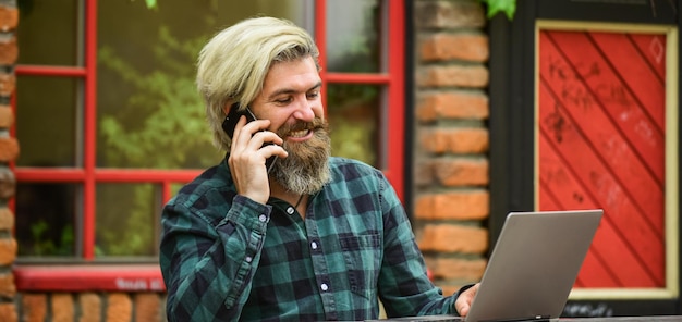 Digitale Welt starten Videokonferenzen Kommunikation per Videoanruf Geschäftsmann mit Laptop und Telefon sitzt im Café Schöner Mann, der an seinem Laptop arbeitet Geschäftsmann, der im Freien mit Computer arbeitet