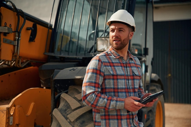 Digitales Tablet in der Hand Mann mit Traktor Landwirtsarbeiter