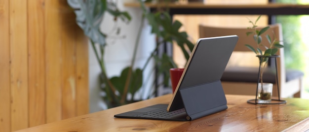 Digitales Tablet mit einer Tastatur auf einem hölzernen Schreibtisch